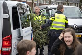 Agenten helpen kinderen met inzamelen kerstbomen