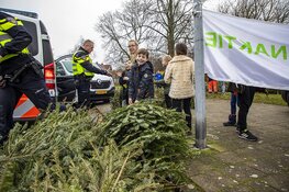 Agenten helpen kinderen met inzamelen kerstbomen