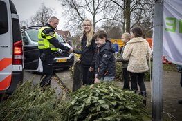 Agenten helpen kinderen met inzamelen kerstbomen