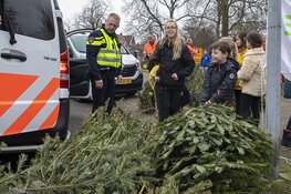 Agenten helpen kinderen met inzamelen kerstbomen