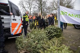 Agenten helpen kinderen met inzamelen kerstbomen