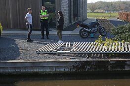 Vrouw rijdt met motor via sloot voortuin binnen